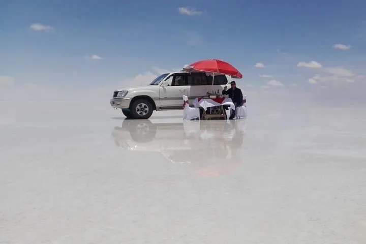 A private 4x4 vehicle parked beside cacti on Incahuasi Island on a Uyuni salt flats tour