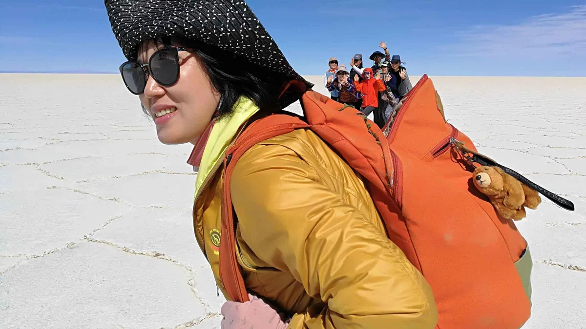 Travelers taking a forced-perspective photo on the salt flat at sunset on a Uyuni salt flats tour
