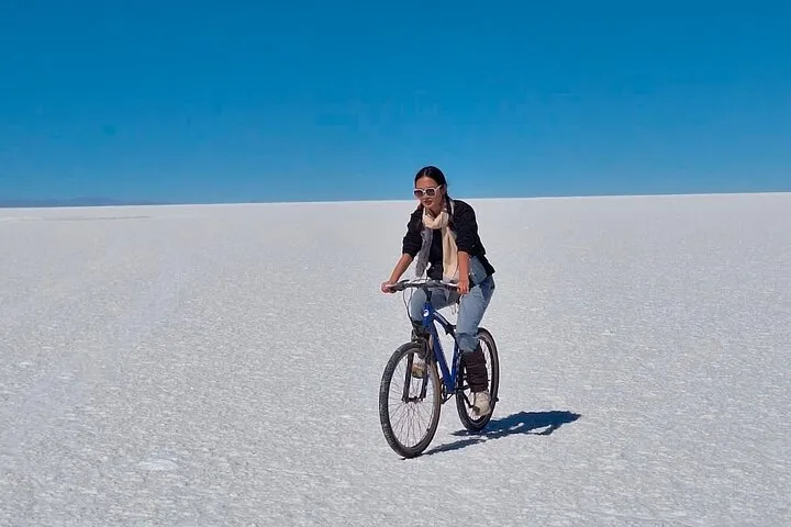 A guide setting up a picnic snack on the salt flat at sunset on a Uyuni salt flats tour