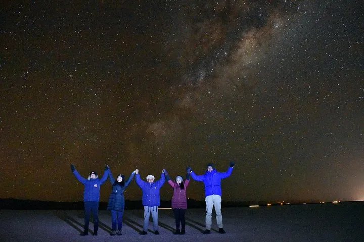 A small group watching the sunset reflected on the salt flat on a Uyuni salt flats tour
